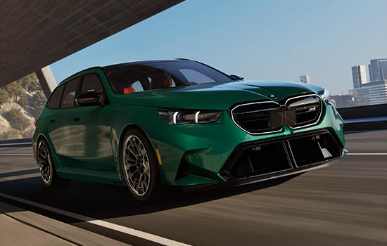Green BMW M5 Touring driving on a city road. | Weatherford BMW of Berkeley in Berkeley CA